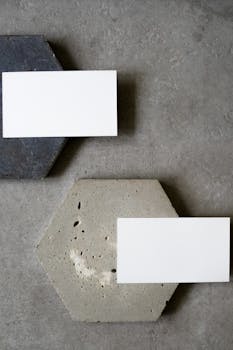 Top view of blank business cards placed on geometric hexagonal concrete surfaces for a modern minimalist mockup.